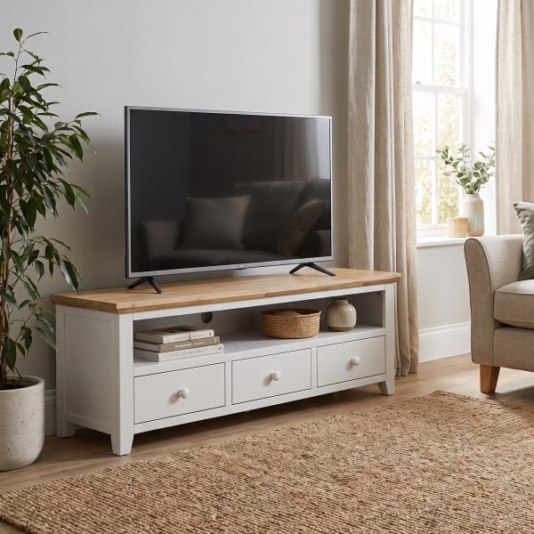 Florence large white painted TV unit with a natural wood top, featuring a wide open media shelf and three storage drawers with round knobs, styled in a living room holding a flat-screen television.