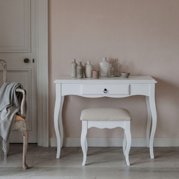 Romance white dressing table and stool set featuring French Rococo curved legs, a central drawer, and a padded seat, styled with an arrangement of rustic bottles against a striped pink wall.
